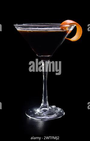 Un verre à martini avec une tranche de zeste d'orange sur le dessus. Le verre est rempli d'un liquide sombre Banque D'Images