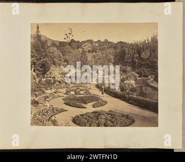 Jardins Ooty. A.T.W. Penn, photographe (britannique, 1849 - 1924, active Inde et Birmanie) Nicholas & Co., éditeur (britannique, active Madas, Inde des années 1860 - 1920) vers 1875 vue d'une section des jardins botaniques gouvernementaux à Ooty, montrant le jardin paysager avec un pavillon couvert de plantes grimpantes, de parterres de fleurs, et un étang. Deux personnes peuvent être vues en train de s'occuper des parterres de fleurs, tandis qu'une troisième personne se tient à proximité au centre de l'image. (Recto, impression) en haut à droite, au crayon : '6 [effacé le plus souvent]' ; en bas à droite, inscrit dans le négatif : '27' ; (recto, monture) en bas à droite, au crayon : 'jardins Banque D'Images