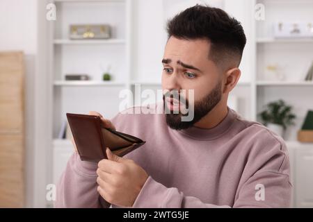 Homme confus avec portefeuille vide à la maison Banque D'Images