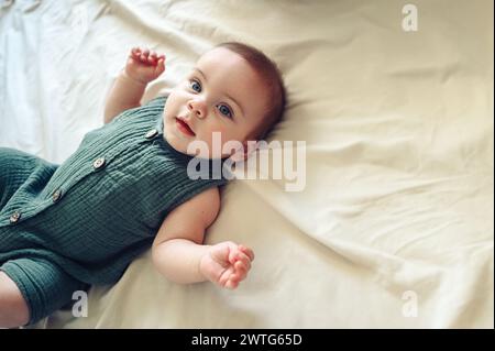 Mignon petit garçon nouveau-né drôle reposant paisiblement sur des draps beiges dans le lit ou la crèche. Modèle d'emballage pour produits pour bébés. Enfant sain, concept d'hôpital et maternité heureuse. Bébé nourrisson. Crèche. Banque D'Images