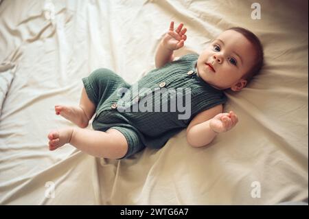 Mignon petit garçon nouveau-né drôle reposant paisiblement sur des draps beiges dans le lit ou la crèche. Modèle d'emballage pour produits pour bébés. Enfant sain, concept d'hôpital et maternité heureuse. Bébé nourrisson. Crèche. Banque D'Images