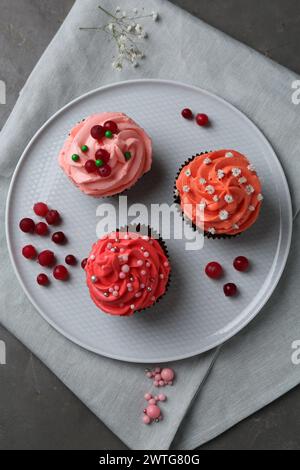 Délicieux cupcakes à la crème rose et aux baies sur table grise, vue de dessus Banque D'Images