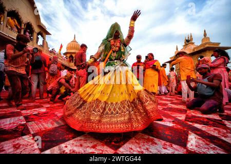 Mathura, Inde. 17 mars 2024. Une femme transgenre danse pendant les célébrations de Laddu Holi au temple Radharani de Barssana - Uttar Pradesh. La fête des couleurs du printemps au temple Radharani dans le village de Barsana de l'Uttar Pradesh en Inde est le premier jour de célébration du principal festival Holi. Ce festival les dévots et les prêtres du temple Barsana se jettent Laddu (doux traditionnel) les uns sur les autres. Holi est un festival de printemps aussi connu comme le festival des couleurs ou le festival de l'amour. Crédit : SOPA images Limited/Alamy Live News Banque D'Images