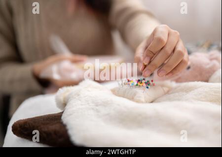 Une image en gros plan d'une femme épinglant une épingle sur un coussin d'épingle, coudre un tissu, fabriquer des articles faits à la main à la maison. concept de travail à l'aiguille Banque D'Images