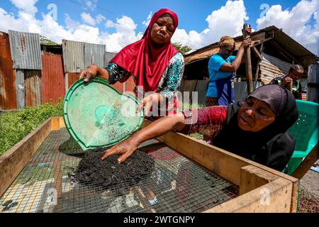 Dar es Salaam, Tanzanie. 16 mars 2024. Les membres d'un groupe de femmes utilisent des coquilles de noix de coco, des écorces de banane séchées et des tiges de manioc séchées pour fabriquer du charbon de bois dans un atelier de rue à Dar es Salaam, en Tanzanie, le 16 mars 2024. Crédit : Herman Emmanuel/Xinhua/Alamy Live News Banque D'Images