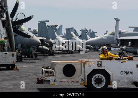 MER DE CHINE MÉRIDIONALE (9 mars 2024) compagnon de bateau de l'US Navy Aviation (manutention) 2e classe Steven Ramirez, de la colonie, au Texas, conduit un tracteur Banque D'Images