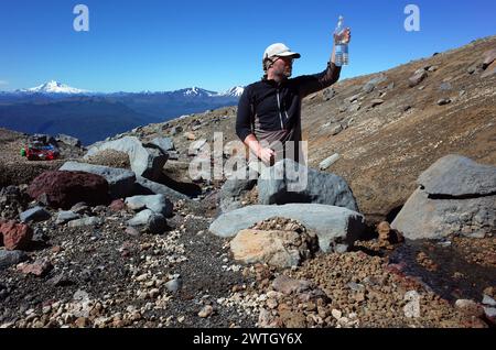 Touriste vérifiant la qualité de l'eau potable en regardant bouteille en plastique, du ruisseau de montagne sur le volcan Puyehue dans le parc national de Puyehue, Los Lag Banque D'Images