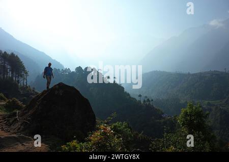 Homme debout sur un gros rocher dans les montagnes de l'Himalaya près de Lukla, Népal Banque D'Images
