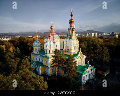 Panorama de drone aérien de la cathédrale de l'Ascension église orthodoxe russe et montagnes de neige en arrière-plan dans le parc Panfilov contre le ciel du coucher du soleil à Almat Banque D'Images