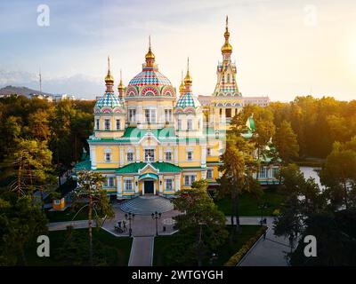 Panorama de drone aérien de la cathédrale de l'Ascension église orthodoxe russe et montagnes de neige en arrière-plan dans le parc Panfilov contre le ciel du coucher du soleil à Almat Banque D'Images