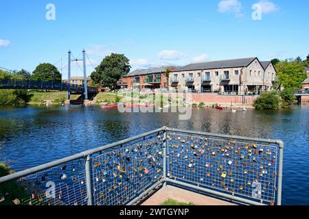 Vue sur le pont suspendu Cricklepit au-dessus de la rivière Exe avec des lovelocks sur des rampes au premier plan et restaurant de quai à l'arrière, Exeter, Royaume-Uni. Banque D'Images