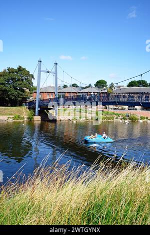 Vue sur le pont suspendu Cricklepit au-dessus de la rivière Exe avec une famille profitant d'une balade à pédalo au premier plan, Exeter, Devon, Royaume-Uni, Europe. Banque D'Images