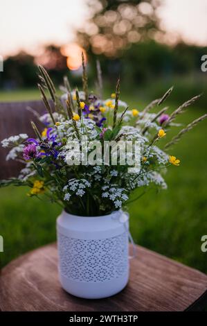 Vase d'extérieur blanc avec fleurs de prairie, herbes et herbe. Une variété colorée de fleurs sauvages d'été. Banque D'Images