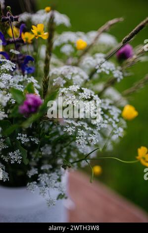 Vase d'extérieur blanc avec fleurs de prairie, herbes et herbe. Une variété colorée de fleurs sauvages d'été. Banque D'Images