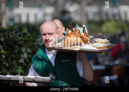 AUTRICHE ; VIENNE ; 20240315 ; les serveurs portent des tableaux avec l'original 'Schweizerhaus Stelze' (pilotis de la maison suisse) à travers le jardin de bière du célèbre restaurant Schweizerhaus dans le parc d'attractions Prater de Vienne pendant l'ouverture de la saison à Vienne le 15 mars 2024. Le restaurant Schweizerhaus est connu pour ses pilotis de porc et sa bière Budweiser. - 20240315 PD16989 crédit : APA-PictureDesk/Alamy Live News Banque D'Images