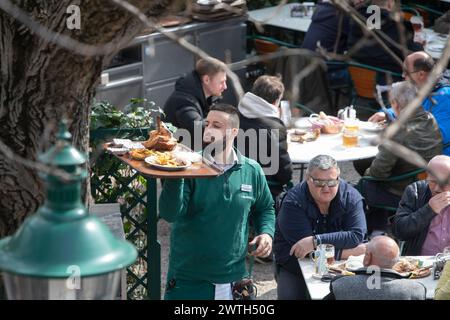 AUTRICHE ; VIENNE ; 20240315 ; les serveurs portent des tableaux avec l'original 'Schweizerhaus Stelze' (pilotis de la maison suisse) à travers le jardin de bière du célèbre restaurant Schweizerhaus dans le parc d'attractions Prater de Vienne pendant l'ouverture de la saison à Vienne le 15 mars 2024. Le restaurant Schweizerhaus est connu pour ses pilotis de porc et sa bière Budweiser. - 20240315 PD16992 crédit : APA-PictureDesk/Alamy Live News Banque D'Images