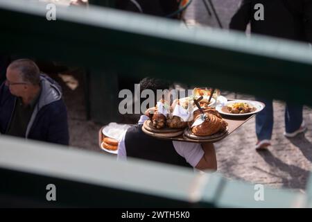 AUTRICHE ; VIENNE ; 20240315 ; les serveurs portent des tableaux avec l'original 'Schweizerhaus Stelze' (pilotis de la maison suisse) à travers le jardin de bière du célèbre restaurant Schweizerhaus dans le parc d'attractions Prater de Vienne pendant l'ouverture de la saison à Vienne le 15 mars 2024. Le restaurant Schweizerhaus est connu pour ses pilotis de porc et sa bière Budweiser. - 20240315 PD16987 crédit : APA-PictureDesk/Alamy Live News Banque D'Images