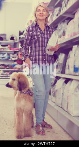 Femelle avec chiot Shepherd afghan choisissent la nourriture pour animaux de compagnie dans le magasin de zoo Banque D'Images