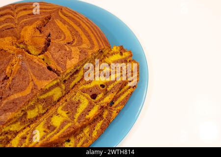 Une tranche de gâteau avec une plaque bleue sur fond blanc. Le gâteau est coupé en morceaux et a un imprimé zèbre dessus Banque D'Images