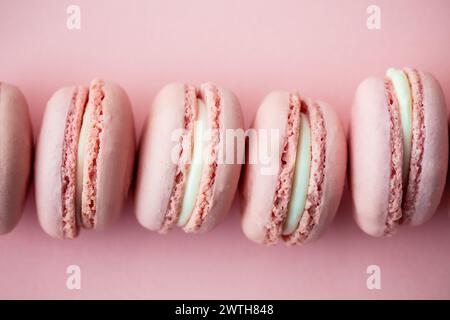 Macarons roses doux parfaitement alignés sur un fond assorti Banque D'Images