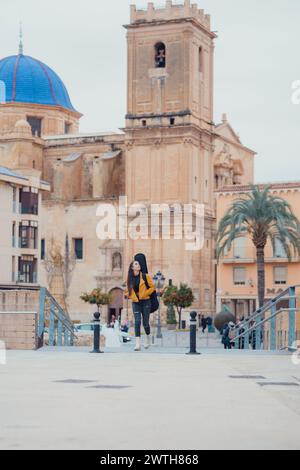 Femme marchant dans la vieille ville d'une ville avec une guitare sur le dos Banque D'Images