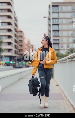 Femme marchant dans une ville avec une guitare sur la main Banque D'Images