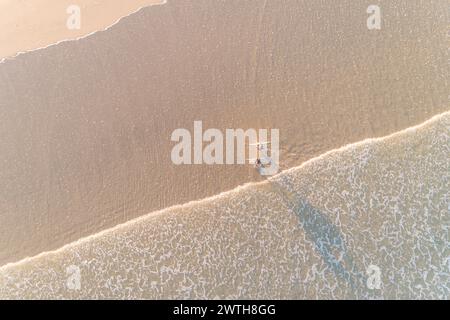 deux surfeurs sur le rivage d'une plage au lever du soleil, vue aérienne par drone. Concept de sports d'été Banque D'Images