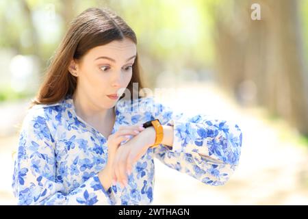 Femme choquée regardant les nouvelles smartwatch dehors Banque D'Images