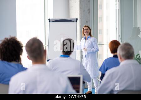 Femme médecin en tant que conférencière à la conférence pour les travailleurs de la santé, équipe médicale assis et présentateur d'écoute. Les experts médicaux fréquentant une formation Banque D'Images