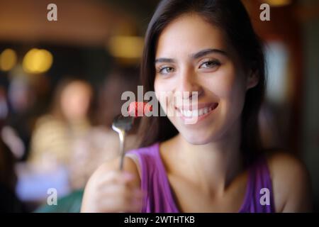 Femme heureuse posant manger de la fraise dans un intérieur de restaurant Banque D'Images