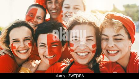 Fans de sport fous souriant à la caméra tout en soutenant leur équipe - supporters de football s'amusant à l'extérieur du stade portant des t-shirts rouges - événement Banque D'Images