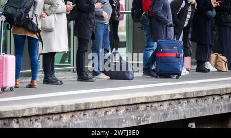 Hanovre, Allemagne. 18 mars 2024. Les voyageurs se tiennent debout avec des sacs et des valises sur une piste à la gare centrale de Hanovre. Les deux parties au conflit salarial à Deutsche Bahn ont repris les négociations. L'entreprise et le syndicat des conducteurs de train GDL sont confiants de parvenir à un accord cette semaine, selon un communiqué de Deutsche Bahn. Crédit : Julian Stratenschulte/dpa/Alamy Live News Banque D'Images