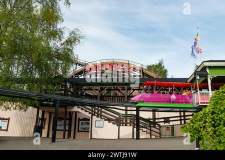 Helsinki, Finlande - 21 mai 2023 : montagnes russes Vuoristorata et train Maisemajuna en mouvement sur fond de ciel dans le parc d'attractions Linnanmaki Banque D'Images