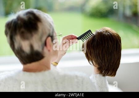 Femme avec alopécie peignant une perruque Banque D'Images