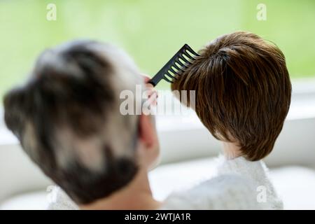 Femme avec alopécie peignant une perruque Banque D'Images