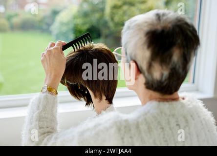 Femme avec alopécie peignant une perruque Banque D'Images