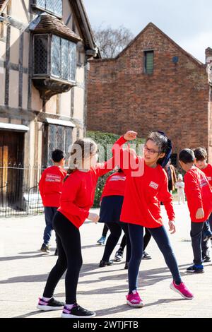 Royaume-Uni, Stratford-upon-Avon. 18/03/2024. Pour célébrer le 10e anniversaire de la semaine de Shakespeare, les élèves de l'école primaire catholique St Gregory présentent leur production de Roméo et Juliette à l'extérieur de l'emblématique lieu de naissance de Shakespeare sur Henley Street. C'est la célébration locale dans le cadre d'une campagne flashmob nationale plus large qui se déroule à travers l'Angleterre. Stratford-upon-Avon accueille une performance spéciale inspirée de l’une des pièces les plus célèbres de Shakespeare le lundi 18 mars, en tant que lieu de naissance de Shakespeare qui marque son 10e anniversaire crédit : Shaun Fellows/Alamy Live News Banque D'Images