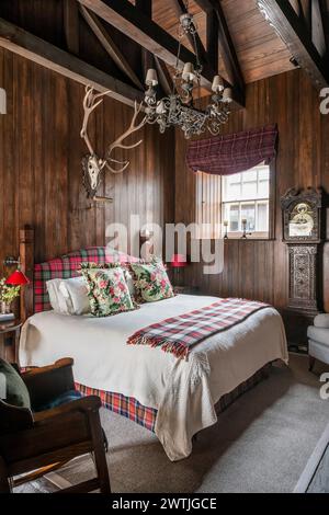 Bois fixés au mur au-dessus du lit avec couverture en tartan dans un hôtel de luxe à Ardfin sur l'île du Jura, Hébrides intérieures, Écosse, Royaume-Uni Banque D'Images