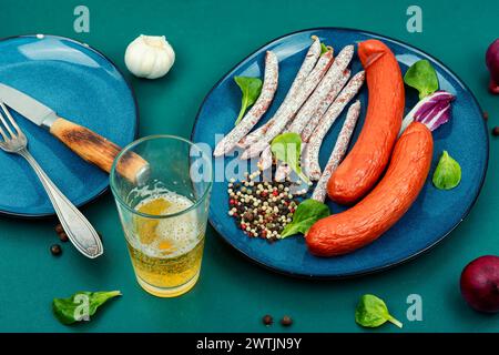 Délicieuses saucisses kabanos, bâtonnets de salami et bière fraîche. Collations appétissantes à la bière. Nourriture Oktoberfest. Banque D'Images