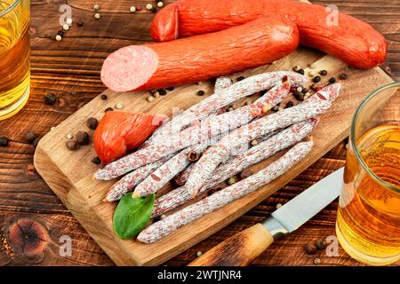 Saucisses kabanos fumées, préparées à partir de viande hachée mélangée avec ajout d'épices. Bâtonnets de salami, saucisses et bière fraîche. Bar ou pub. Banque D'Images