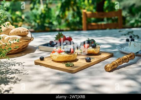 Toast avec fromage à la crème, myrtille, fraise, flocons de noix de coco et herbes pour pique-nique ou brunch d'été. Mini sandwichs sucrés pour un petit déjeuner sain en t Banque D'Images