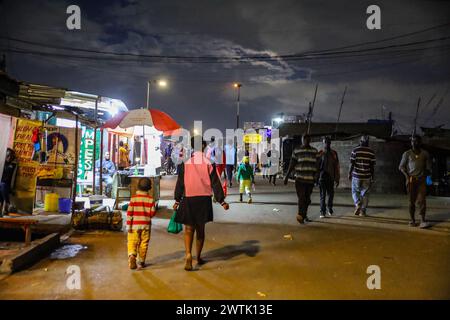 Les résidents rentrent chez eux tard dans la soirée en passant par les rues animées du bidonville de Kibera, Nairobi. Kibera, le plus grand bidonville de Nairobi et d'Afrique, abrite Banque D'Images