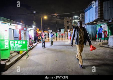 Les résidents rentrent chez eux tard dans la soirée en passant par les rues animées du bidonville de Kibera, Nairobi. Kibera, le plus grand bidonville de Nairobi et d'Afrique, abrite Banque D'Images