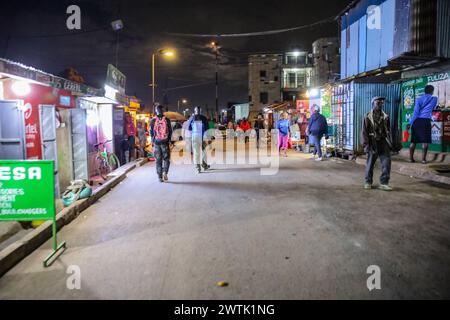 Les résidents rentrent chez eux tard dans la soirée en passant par les rues animées du bidonville de Kibera, Nairobi. Kibera, le plus grand bidonville de Nairobi et d'Afrique, abrite Banque D'Images