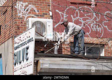 Un couvreur installant une toiture torche dans des magasins à Williamsburg, Brooklyn, New York. En hiver 2024. Banque D'Images