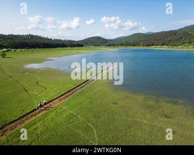 Vue arrière de deux routards sur une promenade détendue, profitant d'un paysage de montagne d'été fantastique et des couleurs de l'environnement, prise de vue aérienne. Excursion nature Banque D'Images