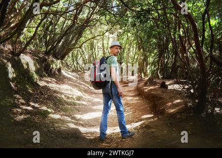 Homme portant un sac à dos se tient au milieu des arbres dans une forêt dense. Tenerife, Espagne Banque D'Images