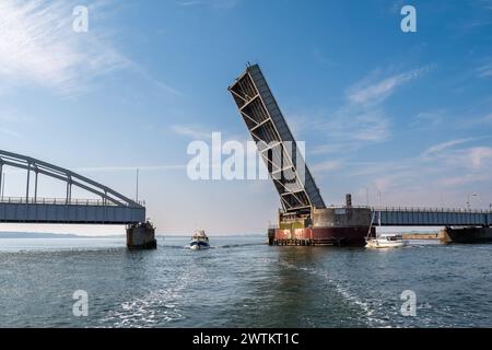 Bateau à moteur et voilier traversant le pont ouvert d'Oddesund sur le détroit d'Oddesund dans le Limfjord, Midtjylland, Danemark Banque D'Images