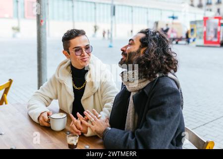 Couple masculin profitant du temps ensemble tout en prenant un café dans un café en plein air. Banque D'Images