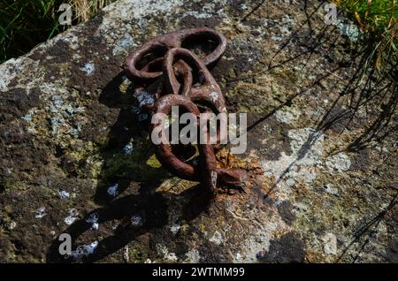 Chaîne rouillée attachée à un gros bloc de béton utilisé pour stationner les machines, trouvé sur la rive de Strangford Lough. Banque D'Images